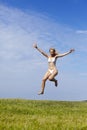 The happy woman in white bikini jumps in a summer green field against the blue sky Royalty Free Stock Photo