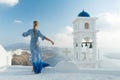 Happy woman in white and blue dress enjoying her holidays on Santorini, Greece. View on Caldera and Aegean sea from