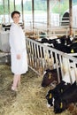 Happy woman in white coat stands near eating small