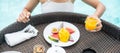 Happy woman in white swimsuit having Floating Breakfast tray in luxury pool hotel, young female with enjoy in tropical resort. Royalty Free Stock Photo