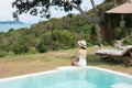 Happy woman in white swimsuit swimming in luxury pool hotel against beautiful view, young female with hat enjoy in tropical resort Royalty Free Stock Photo