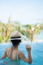 Happy woman in white swimsuit swimming in luxury pool hotel, young female with hat enjoy in tropical resort. Relaxing, summer Royalty Free Stock Photo