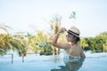 Happy woman in white swimsuit swimming in luxury pool hotel, young female with hat enjoy in tropical resort. Relaxing, summer Royalty Free Stock Photo