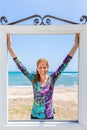 Happy woman in window in front of blue sea and beach Royalty Free Stock Photo