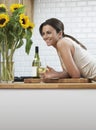 Happy Woman With Wineglass Leaning On Counter