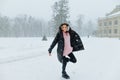 Happy woman in winter clothes fooling around on a walk in the snow with a smile on her face, looking at the camera and smiling Royalty Free Stock Photo