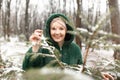 Happy woman in winter forest. Female portrait in park, selective focus. Joyful woman touch snow branch of green spruce.