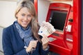 Happy woman withdrawing cash from ATM