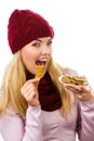 Happy woman in woolen cap and shawl eating gingerbread cookies, white background, christmas time Royalty Free Stock Photo