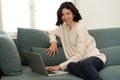 Happy woman working on laptop surfing on the internet and social media sitting on sofa at home Royalty Free Stock Photo