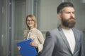 Happy woman with blurred man in foreground. Business woman in glasses hold file folder. secretary smile with office