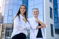 Happy women in business suits with folder standing before big business office