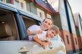 Happy woman and child look out of a car window. Cheerful boy with his mother are sitting in the back seat of the car and Royalty Free Stock Photo