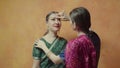 Closeup female sticking red bindi point to friend