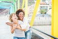 Happy women friends laughing and walking on colorful bridge - Young girls having fun in summer time around city - Youth lifestyle