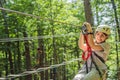 Happy women girl female gliding climbing in extreme road trolley zipline in forest on carabiner safety link on tree to