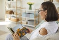 Happy woman sitting on couch and looking through pictures in her family photo album Royalty Free Stock Photo