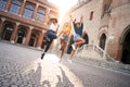 Happy women having fun together in Venice. Three young women jump holding hans, multiracial group laughing