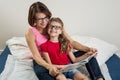 Happy woman with her daughter child, reading together a book a