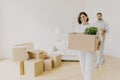 Happy woman and her husband carry boxes with personal belongings, being busy during relocation in other place for living, enter Royalty Free Stock Photo