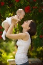 Happy woman holding in arm a baby in a garden. Happy family.