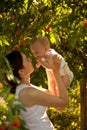 Happy woman holding in arm a baby in a garden. Happy family. Royalty Free Stock Photo