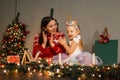 Happy woman in a knitted red sweater with a little girl in a unicorn costume with a full skirt having fun in a cozy living room