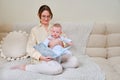 Happy woman mother with infant baby reading book on home sofa in living room Royalty Free Stock Photo