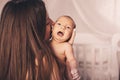 Happy woman mother kissing a newborn baby girl in her arms at home. Mom with a child in her hands Royalty Free Stock Photo