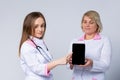 Happy women, professional nurses, female doctors wear white uniform show digital tablet mock up blank empty screen