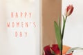 Happy women`s day text on pink tulip in vase on window in soft m