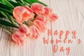 Happy women`s day text on pink tulips on white rustic wooden bac