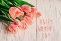 Happy women`s day text on pink tulips on white rustic wooden bac