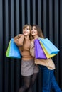 Happy women with shopping bags in fur coats posing on city street Royalty Free Stock Photo