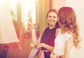 Happy women with shopping bags at shop window Royalty Free Stock Photo