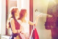 Happy women with shopping bags at shop window Royalty Free Stock Photo