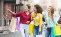 Happy women with shopping bags walking along city street Royalty Free Stock Photo