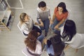 Happy women sitting in circle and holding hands in session with coach or in group therapy