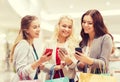 Happy women with smartphones and shopping bags Royalty Free Stock Photo