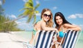 Happy women sunbathing in chairs on summer beach