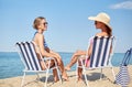 Happy women sunbathing in lounges on beach Royalty Free Stock Photo