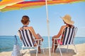 Happy women sunbathing in lounges on beach Royalty Free Stock Photo