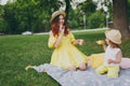 Happy woman in yellow dress play, rest in park have fun, amuse with little cute child baby girl hold soap bubble blower Royalty Free Stock Photo