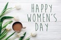 Happy womens day text sign on tulips and coffee on white wooden