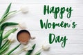 Happy womens day text sign on tulips and coffee on white wooden