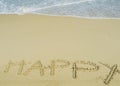 Happy wording written on sand next the sea. relaxing and enjoying summer vacation Royalty Free Stock Photo