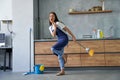 Happy worker. Full length shot of cheerful young woman, cleaning lady pretending to sing a song, holding broom while