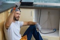 Happy worker. Portrait of cheerful young handyman holding a hammer and an adjustable wrench in his hands while sitting Royalty Free Stock Photo