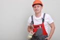 Happy worker in red uniform, protective hard hat holding bundle of dollars, cash money on white background. Male worker for Royalty Free Stock Photo
