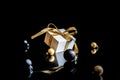 Happy xmas. White gift box with golden ribbon, New Year balls and winter tree in Christmas composition on black background for Royalty Free Stock Photo